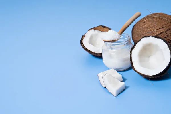 Coco com óleo de coco sobre mesa azul — Fotografia de Stock