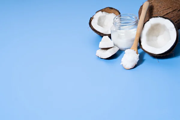Coco com óleo de coco sobre mesa azul — Fotografia de Stock