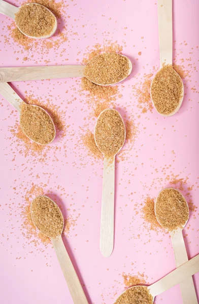 Καστανή ζάχαρη με ξύλινο κουτάλι στο ροζ τραπέζι — Φωτογραφία Αρχείου