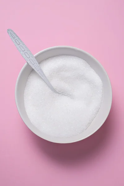 White sugar in white bowl on pink table — Stock Photo, Image