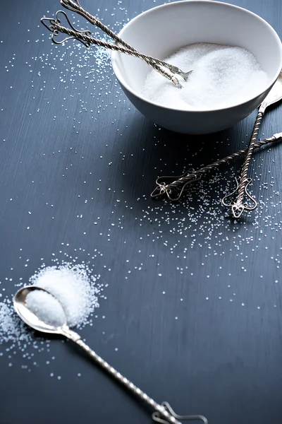 黒いテーブルの上のスプーンで白い砂糖 — ストック写真