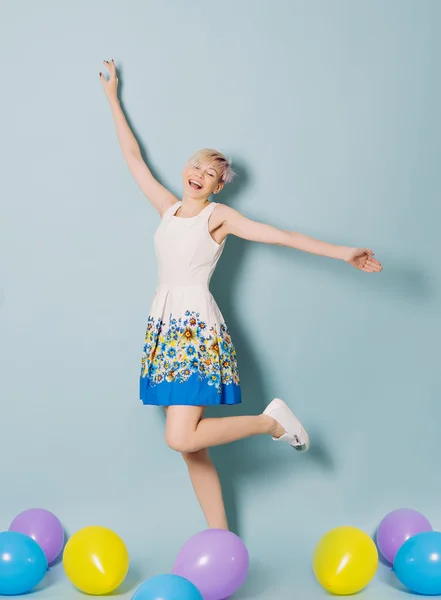 Dívka se bavit s barevnými balónky na modrém pozadí — Stock fotografie