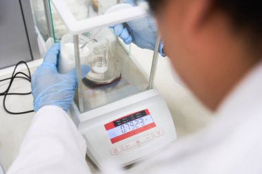 Kimya laboratuvarında hammaddelerin tartılması, laboratuvar teknisyeni