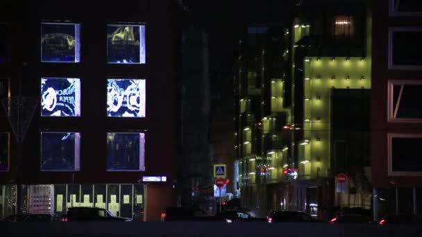 Дзеркальне відображення реклами світилами вікнами будинків по ночах — стокове відео