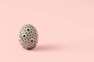 Pembe arka planda şaşı gözlerle kaplı doğal Paskalya yumurtası. Komik tatil konsepti.