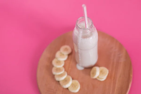 Gustoso frullato di banana su sfondo rosa — Foto Stock