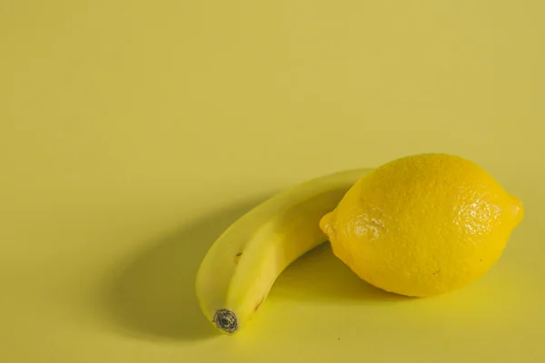 Banan och citron på gul bakgrund — Stockfoto