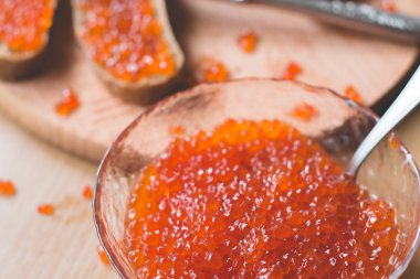 Kırmızı havyar sandviç ile gümüş bıçak kızartır, kase lezzetli kırmızı havyar kaşık ve taze ev yapımı sağlıklı bir ahşap masa arka plan üzerinde ekmek