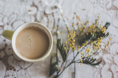 Tığ işi masa örtüsü üzerinde rustik dekorasyonda tüm sevimli bir pastel sarı fincan sütlü siyah çay