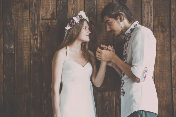 Young and beautiful bride and groom are having a good fun time and happy together while shooting a wedding photosession in studio with rustic decorations and wooden backgrounds — Stock Photo, Image