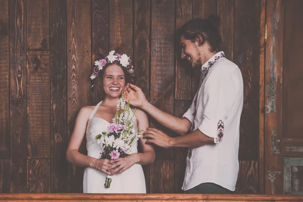 Giovani e bellissimi sposi si divertono e si divertono insieme durante le riprese di una foto di nozze in studio con decorazioni rustiche e sfondi in legno — Foto Stock