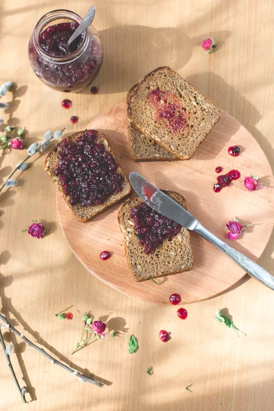 Fresh baked homemade healthy bread with blackcurrant jam - homemade marmalade with fresh organic fruits from garden. In rustic decoration, fruit jam on wooden table background. Perfect sweet breakfast — Stock Photo, Image