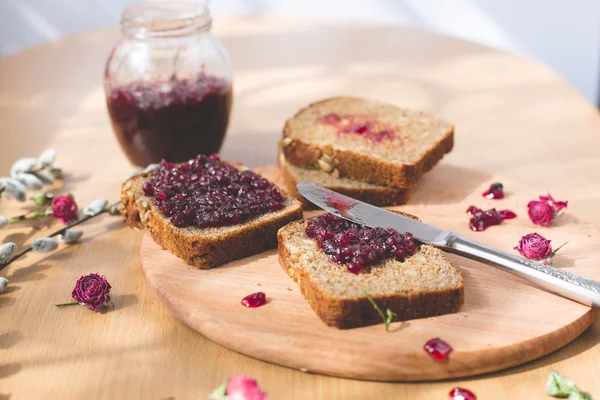 Fresh baked homemade healthy bread with blackcurrant jam - homemade marmalade with fresh organic fruits from garden. In rustic decoration, fruit jam on wooden table background. Perfect sweet breakfast — Stock Photo, Image