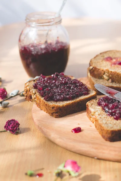 Fresh baked homemade healthy bread with blackcurrant jam - homemade marmalade with fresh organic fruits from garden. In rustic decoration, fruit jam on wooden table background. Perfect sweet breakfast — Stock Photo, Image