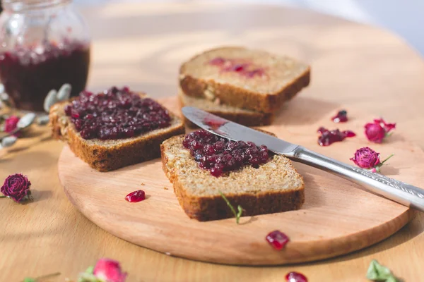 Fresh baked homemade healthy bread with blackcurrant jam - homemade marmalade with fresh organic fruits from garden. In rustic decoration, fruit jam on wooden table background. Perfect sweet breakfast — Stock Photo, Image