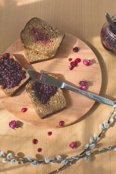 Fresh baked homemade healthy bread with blackcurrant jam - homemade marmalade with fresh organic fruits from garden. In rustic decoration, fruit jam on wooden table background. Perfect sweet breakfast — Stock Photo, Image