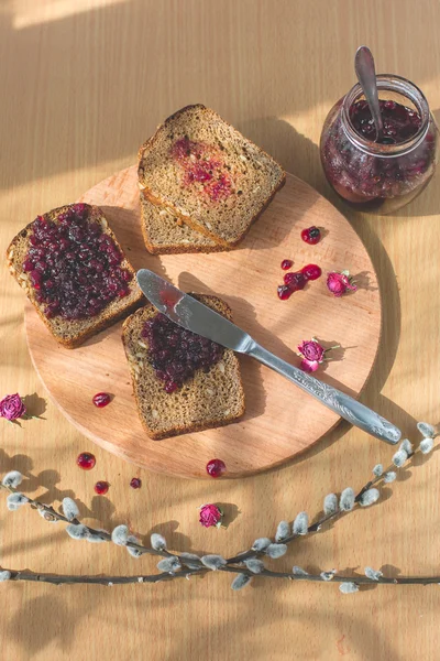 Fresh baked homemade healthy bread with blackcurrant jam - homemade marmalade with fresh organic fruits from garden. In rustic decoration, fruit jam on wooden table background. Perfect sweet breakfast — Stock Photo, Image