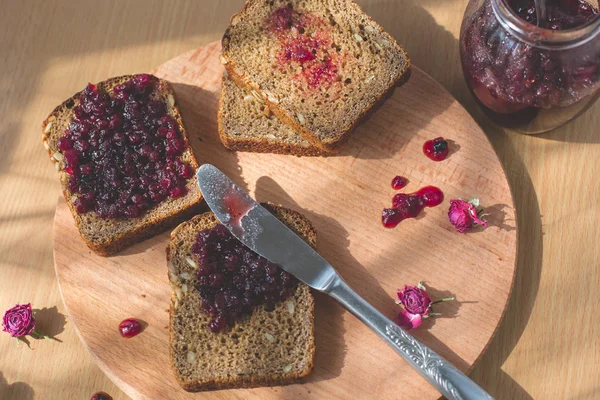 Fresh baked homemade healthy bread with blackcurrant jam - homemade marmalade with fresh organic fruits from garden. In rustic decoration, fruit jam on wooden table background. Perfect sweet breakfast — Stock Photo, Image