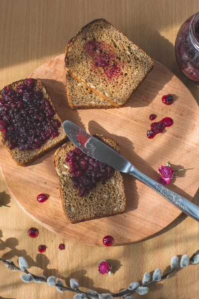 Fresh baked homemade healthy bread with blackcurrant jam - homemade marmalade with fresh organic fruits from garden. In rustic decoration, fruit jam on wooden table background. Perfect sweet breakfast — Stock Photo, Image