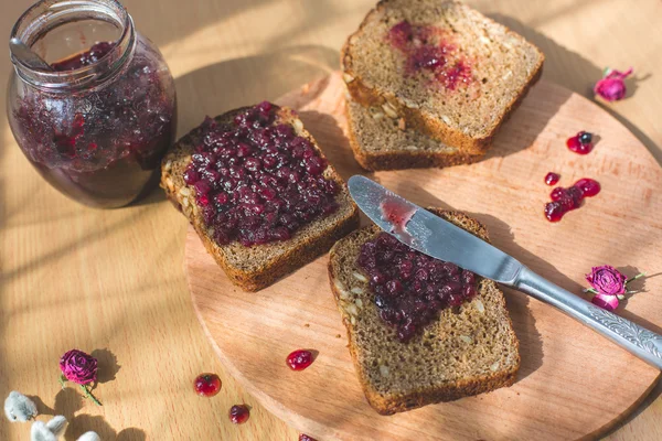 Fresh baked homemade healthy bread with blackcurrant jam - homemade marmalade with fresh organic fruits from garden. In rustic decoration, fruit jam on wooden table background. Perfect sweet breakfast — Stock Photo, Image