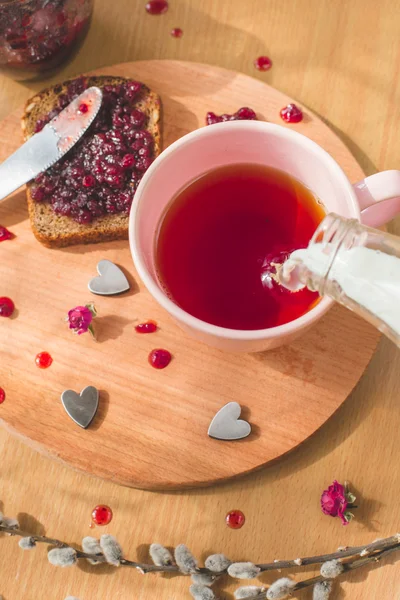 Cup of tea pouring milk, fresh baked healthy bread with blackcurrant jam - homemade marmalade with fresh organic fruits from garden. rustic decoration, fruit jam on wooden table background, breakfast. — Stock Photo, Image