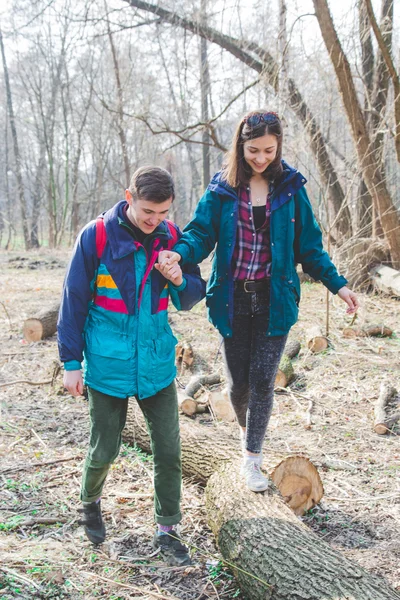 Joven hermosa feliz hipster pareja morena chica y chico tener gran diversión tiempo mientras viaja y caminar en el bosque — Foto de Stock