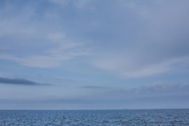 Sakin bir deniz ve mavi gökyüzü ile kalın bir sis puslu güneş