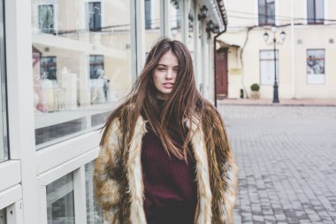 Genç hipster çok güzel beyaz stilysh ve güzel esmer saçlı trendy kız açık havada, cadde ve ahşap serin arka arka plan üzerinde rüzgarlı bahar günü sırasında gülümseyen eğlenceli sahip