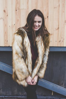 Genç hipster çok güzel beyaz stilysh ve güzel esmer saçlı trendy kız açık havada, cadde ve ahşap serin arka arka plan üzerinde rüzgarlı bahar günü sırasında gülümseyen eğlenceli sahip