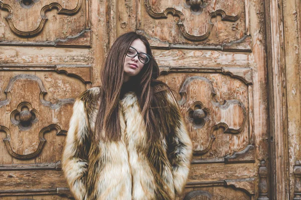 Hipster muda sangat indah stilysh Kaukasia dan gadis trendi dengan rambut cokelat cantik adalah bersenang-senang tersenyum di luar ruangan di latar belakang jalan-jalan dan kayu dingin latar belakang selama musim semi berangin — Stok Foto