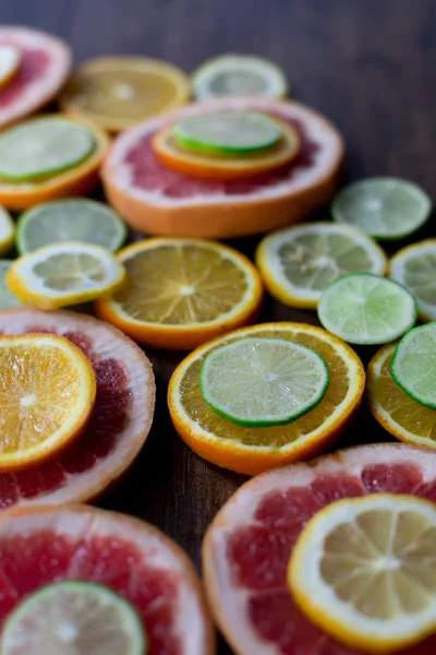 cutted citrus mix lemon grapefruit lime and orange in geometrical shapes on dark wood rustic background  soft focus overhead-angle shot