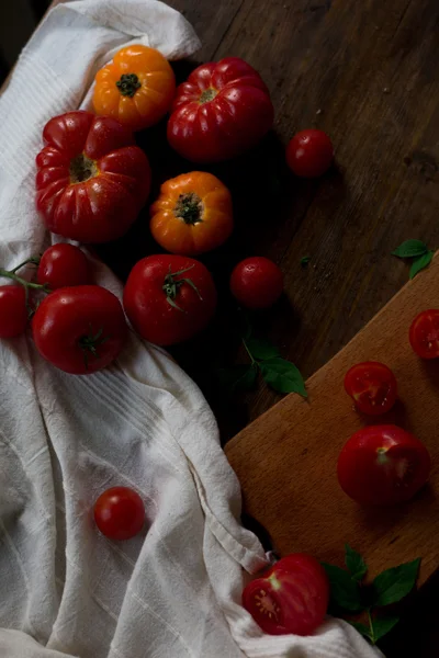 Mix of fresh organic red yellow and cherry tomatoes with water drops from farmers market decorated in rustic style on a dark wood background soft focus overhead-angle shot — Stock Photo, Image