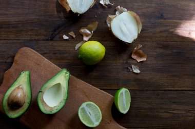 Avokado Guakamole hazırlık süreci tüm ingridients tablo kireç, soğan, tüm organik ve koyu ahşap rustik tarzı arka plan yumuşak odak ek yük-açı vuruşta taze avokado