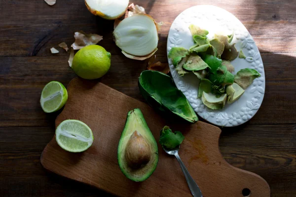 Preparation of avocado guacamole in process all ingridients on table lime, onion, avocado all organic and fresh on dark wood rustic style background soft focus overhead-angle shot — Stock Photo, Image