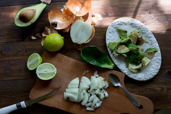Preparation of avocado guacamole in process all ingridients on table lime, onion, avocado all organic and fresh on dark wood rustic style background soft focus overhead-angle shot — Stock Photo, Image