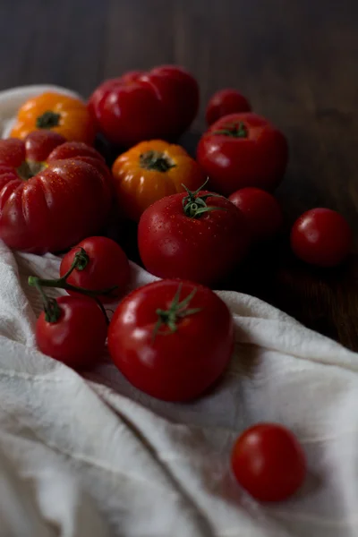 Mix of fresh organic red yellow and cherry tomatoes with water drops from farmers market decorated in rustic style on a dark wood background soft focus overhead-angle shot — Stock Photo, Image