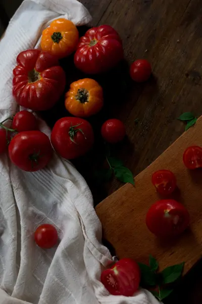 Mix of fresh organic red yellow and cherry tomatoes with water drops from farmers market decorated in rustic style on a dark wood background soft focus overhead-angle shot — Stock Photo, Image