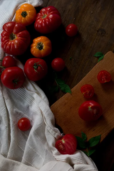 Mix of fresh organic red yellow and cherry tomatoes with water drops from farmers market decorated in rustic style on a dark wood background soft focus overhead-angle shot — Stock Photo, Image