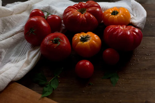 Mistura de tomates frescos orgânicos vermelhos amarelos e cereja com gotas de água do mercado agricultores decorados em estilo rústico em um fundo de madeira escura foco suave tiro de ângulo aéreo — Fotografia de Stock