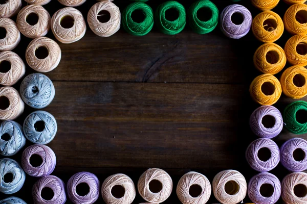 Hilos de hilos para tejer en diferentes colores marco con espacio vacío para texto madera oscura fondo rústico — Foto de Stock
