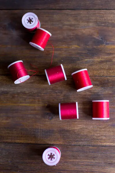 A hímzések és a varrás összetétele a sötét fa asztal rusztikus vörös szálak — Stock Fotó