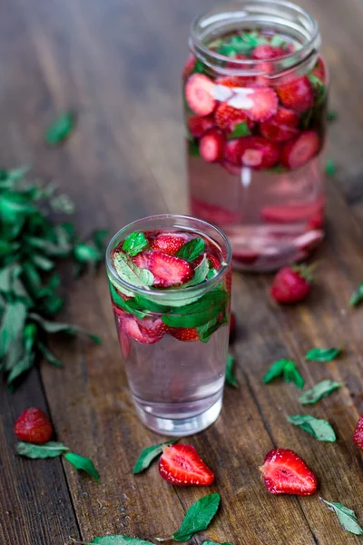 Strawberry mint infused water decorated in rustic style on dark wood table background — Stock Photo, Image