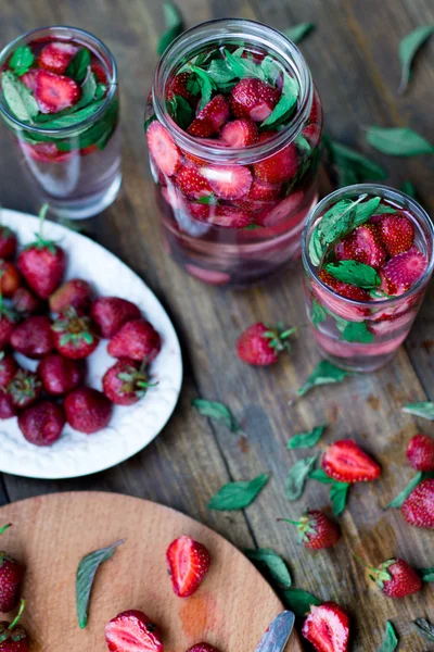 Strawberry mynta infunderas vatten inredda i rustik stil på mörka bord av trä bakgrund — Stockfoto