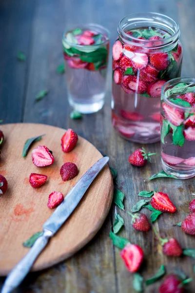 Strawberry mynta infunderas vatten inredda i rustik stil på mörka bord av trä bakgrund — Stockfoto