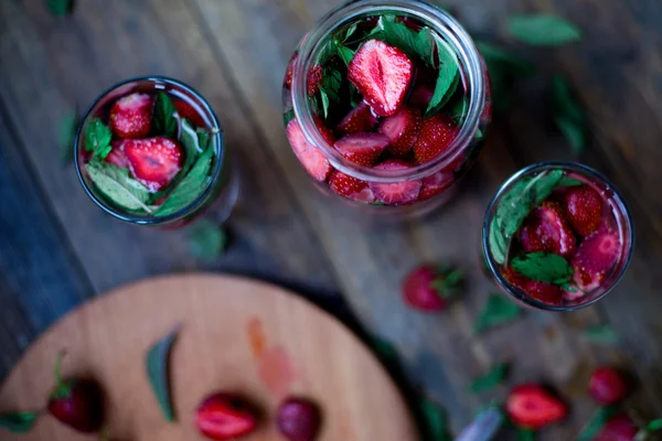 Strawberry mynta infunderas vatten inredda i rustik stil på mörka bord av trä bakgrund — Stockfoto
