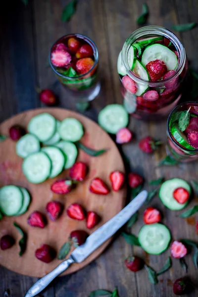 Strawberry mint cucumber infused water decorated in rustic style on dark wood table background — Stock Photo, Image