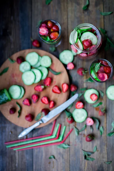 Fresa menta pepino infundido agua decorada en estilo rústico sobre fondo de mesa de madera oscura —  Fotos de Stock