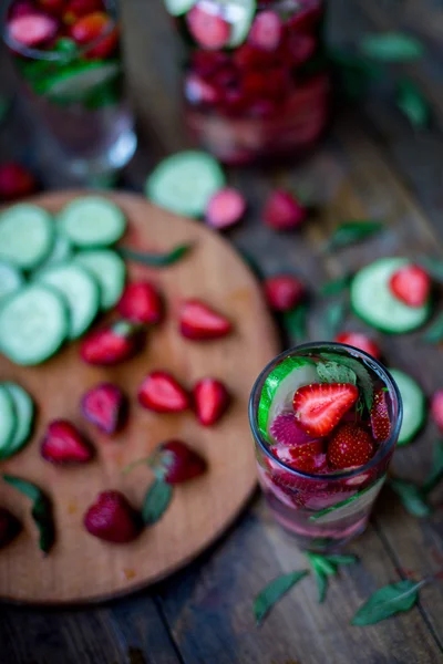 Fresa menta pepino infundido agua decorada en estilo rústico sobre fondo de mesa de madera oscura —  Fotos de Stock