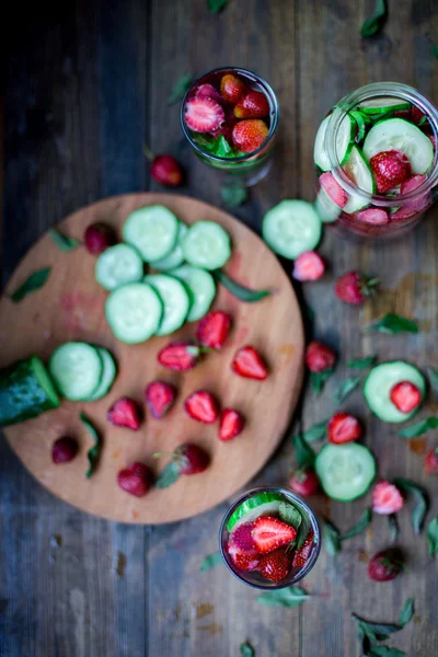 Fresa menta pepino infundido agua decorada en estilo rústico sobre fondo de mesa de madera oscura —  Fotos de Stock