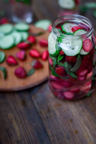 Fresa menta pepino infundido agua decorada en estilo rústico sobre fondo de mesa de madera oscura —  Fotos de Stock